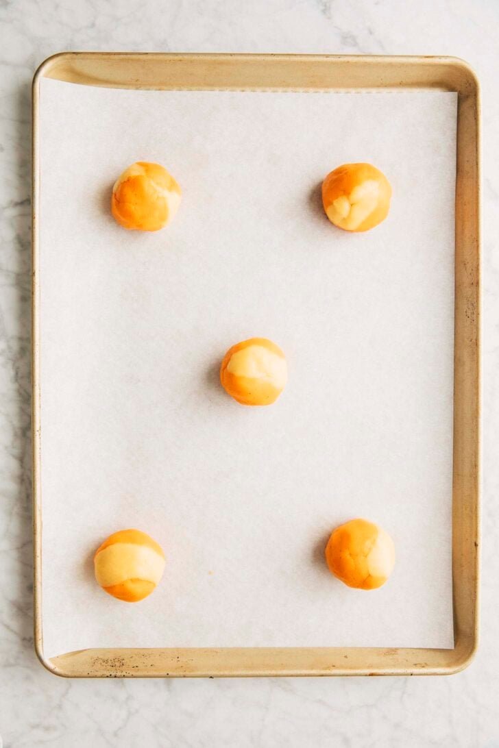 photo showing 5 cookie dough balls arranged in a hopscotch formation on a half sheet pan