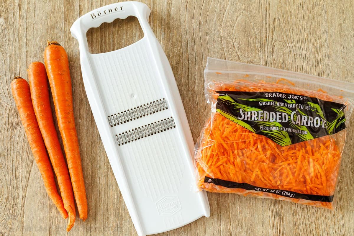 Spicy Korean Carrot Salad packs so much flavor into one crowd-pleasing side dish. The easy dressing melds the whole salad together in minutes. Carrots and and mandolin next to a bag of shredded carrots for Spicy Korean Carrot Salad recipe