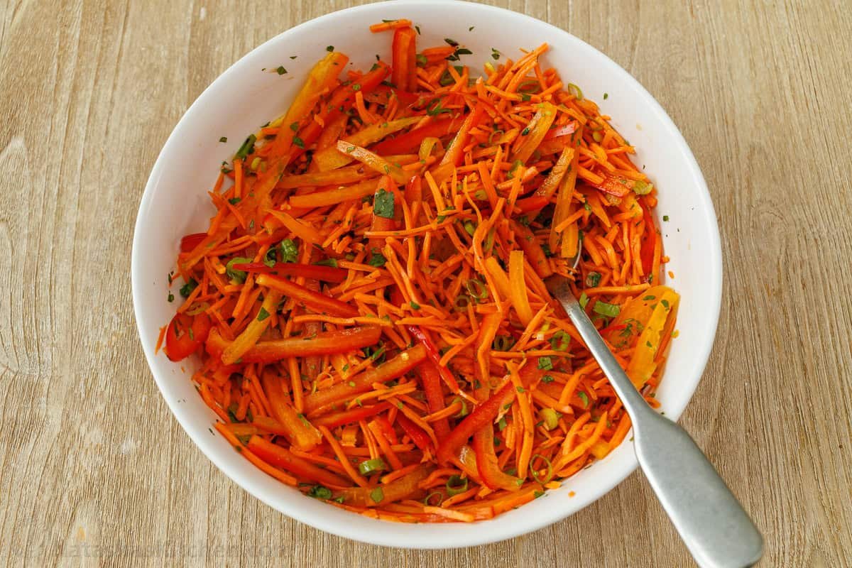 Spicy Korean Carrot Salad packs so much flavor into one crowd-pleasing side dish. The easy dressing melds the whole salad together in minutes. mixing shredded vegetables in a bowl with dressing