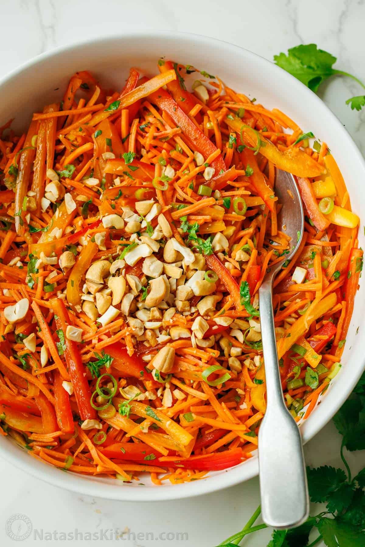 Spicy Korean Carrot Salad packs so much flavor into one crowd-pleasing side dish. The easy dressing melds the whole salad together in minutes. Cashews on top of a Spicy Korean Carrot Salad with peppers and spicy dressing