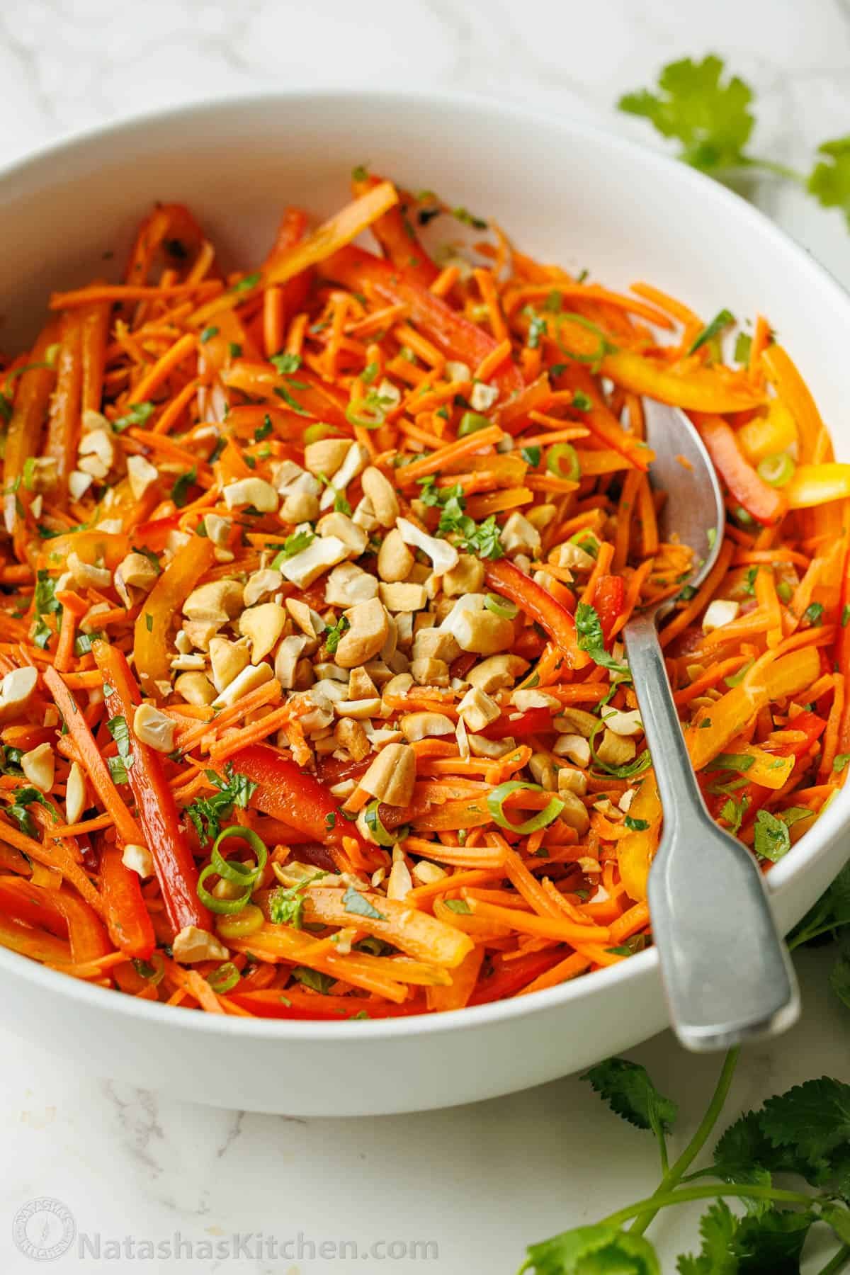 Spicy Korean Carrot Salad packs so much flavor into one crowd-pleasing side dish. The easy dressing melds the whole salad together in minutes. Spicy Korean Carrot Salad recipe with a spoon garnished with cashew nuts