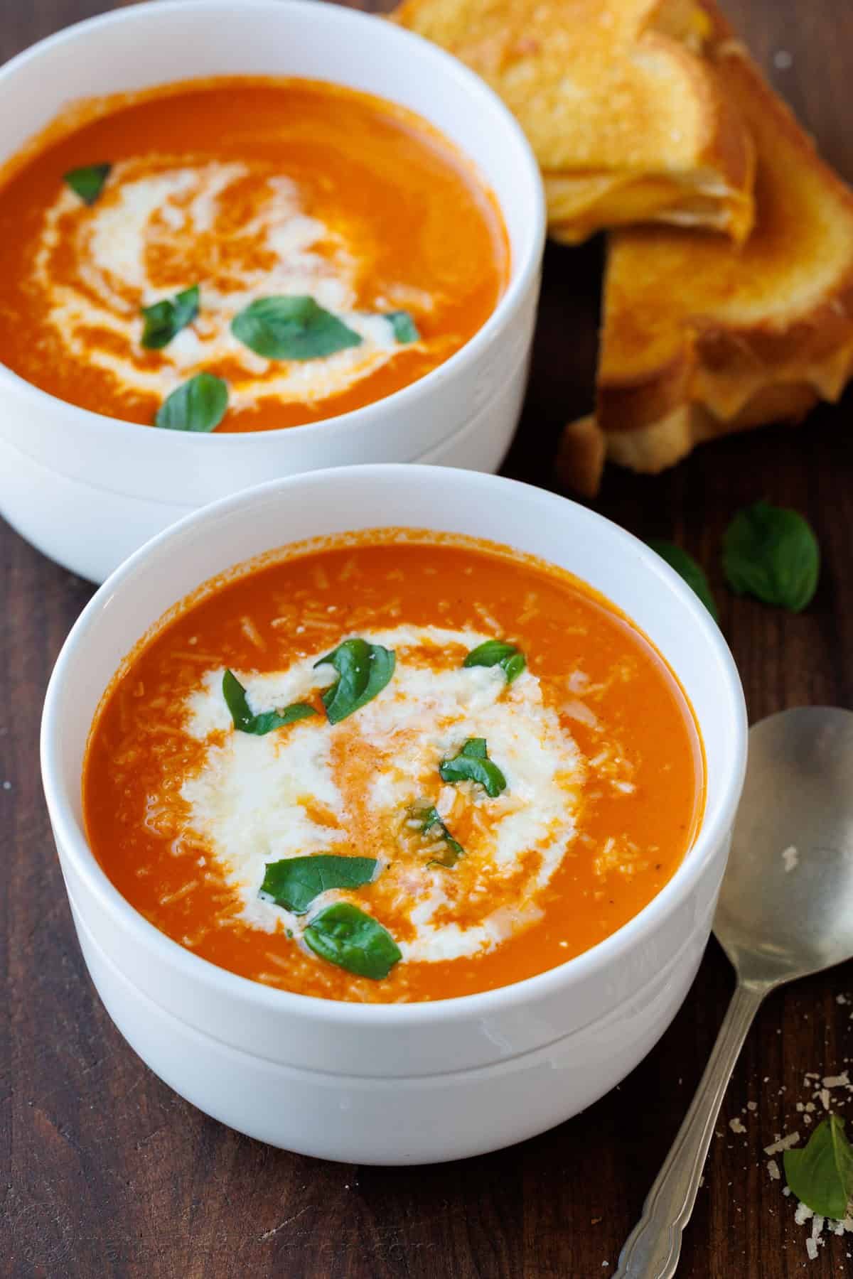 Two bowls of Roasted Tomato soup recipe with Grilled Cheese and a spoon