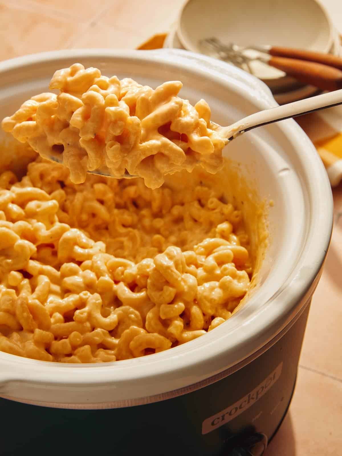 Crock pot mac and cheese with a spoon taking out a big scoop.