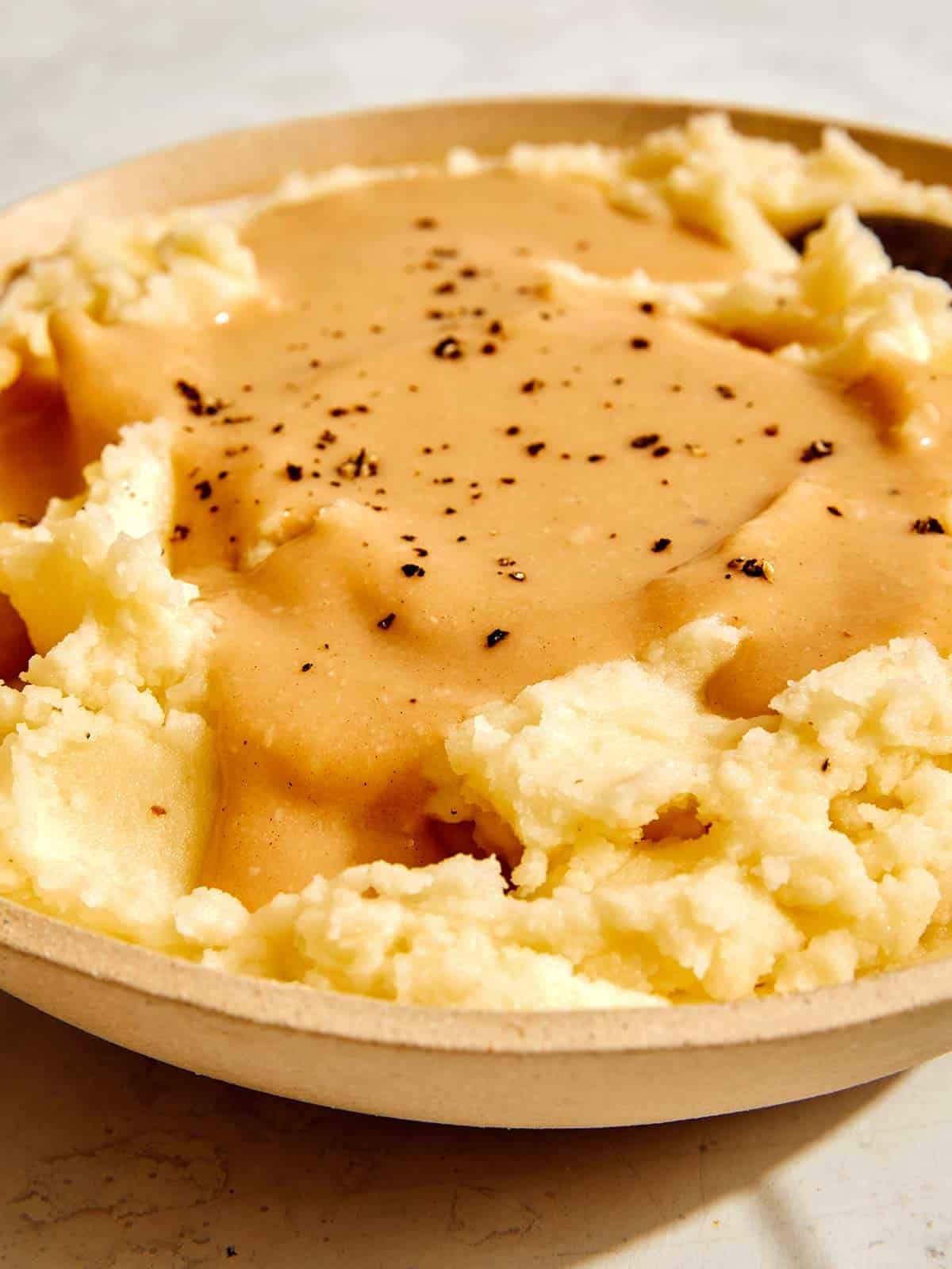 Roasted garlic gravy recipe poured over mashed potatoes.