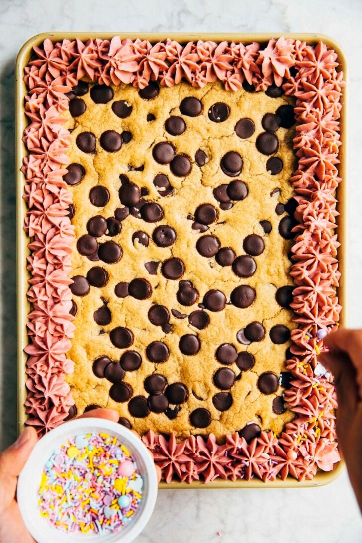 photo of michelle from hummingbird high sprinkling sprinkles onto the cookie cake frosting