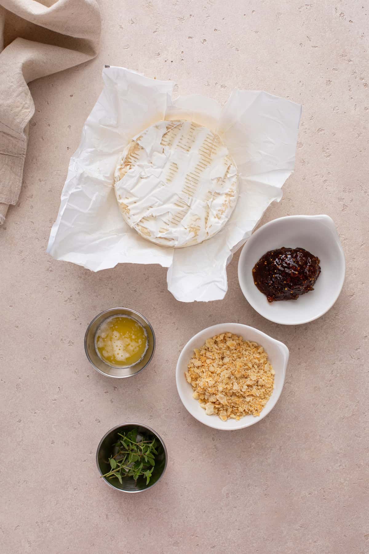 Ingredients for baked brie with jam arranged on a countertop.