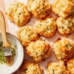 Cheddar bay biscuits on a surface with butter topping on the side.