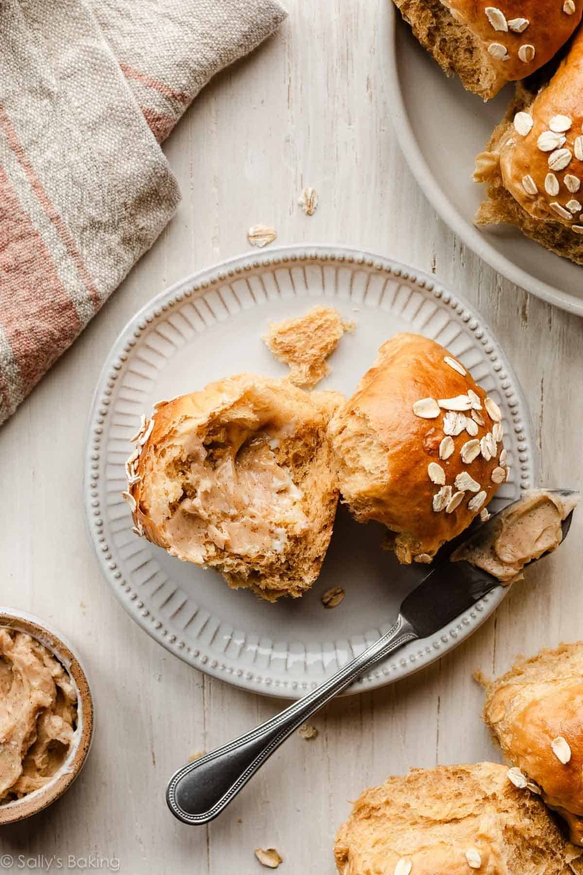oatmeal molasses dinner roll cut in half on plate.