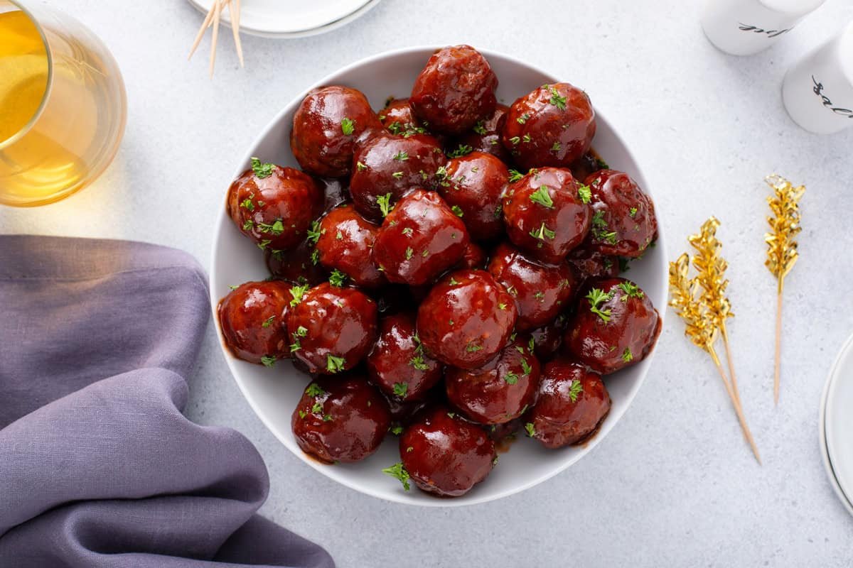 Overhead view of cranberry meatballs in a white serving bowl.