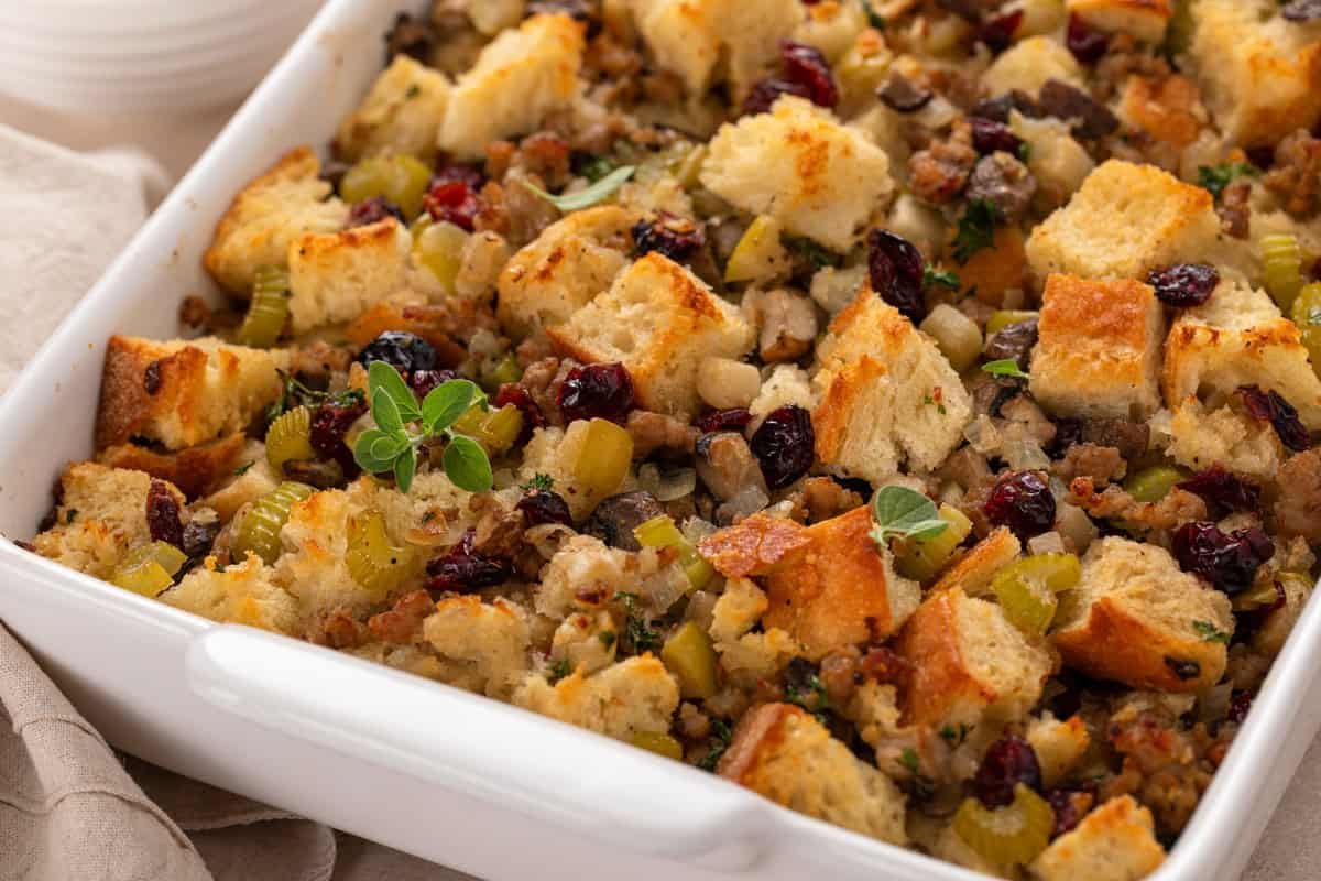 Close up of sausage and cranberry stuffing in a white casserole dish.