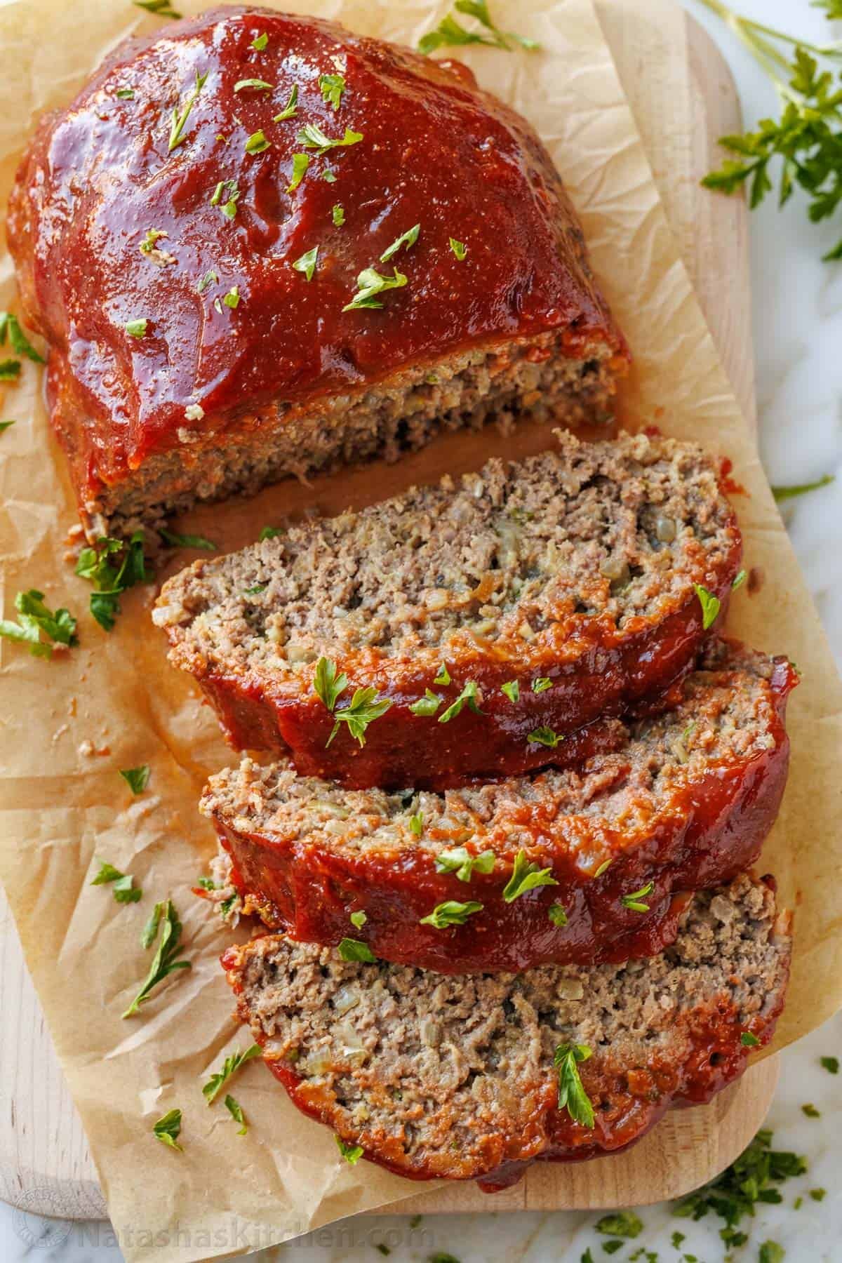 Juicy sliced meatloaf on a cutting board garnished with parsley