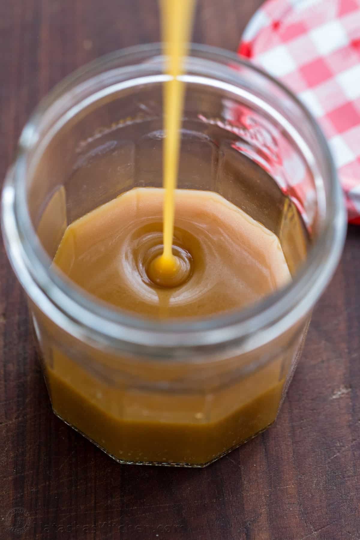 drizzling ice cream topping into a mason jar for storage