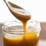Spoon drizzling homemade butterscotch sauce into a mason jar