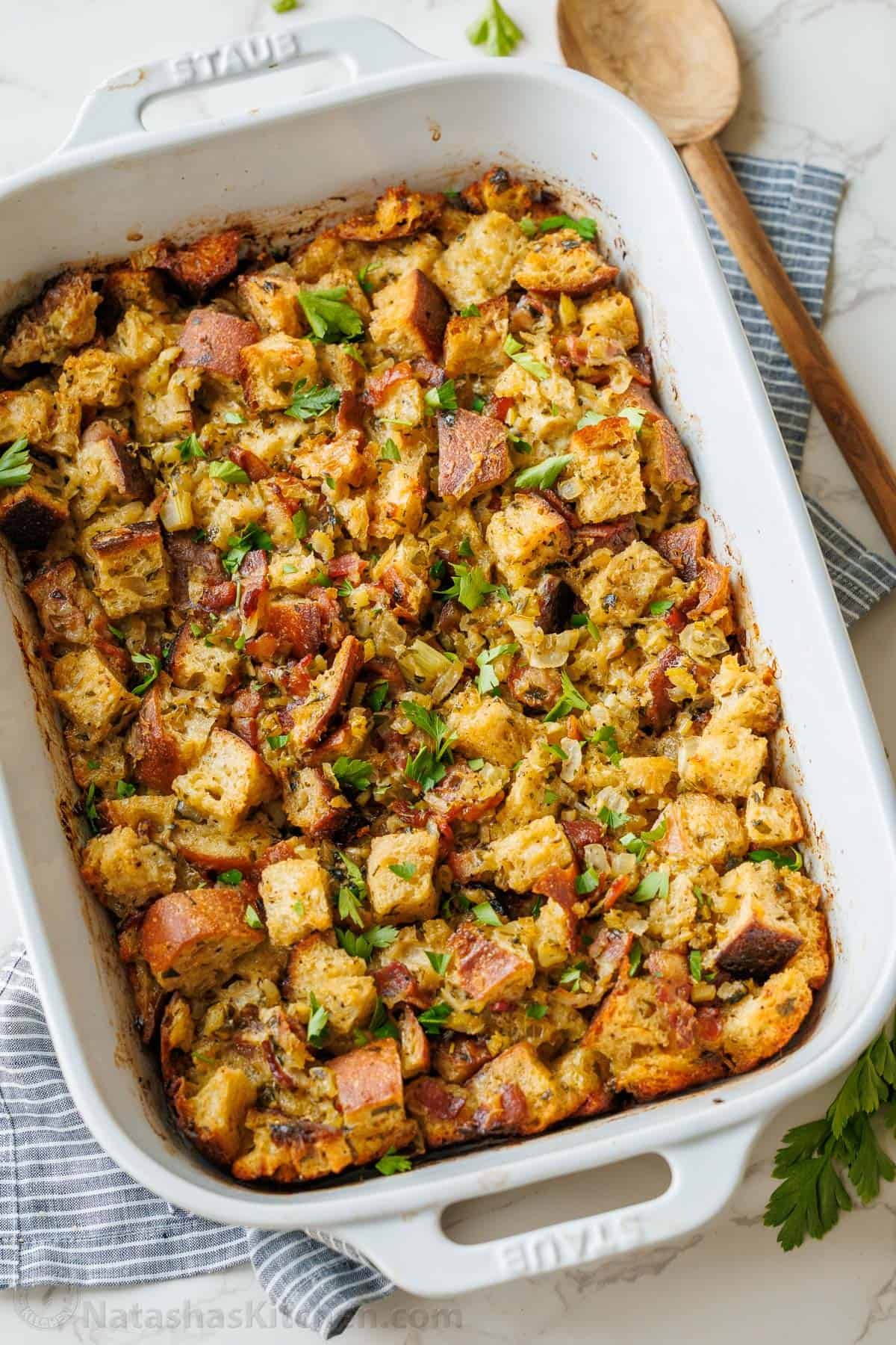 Sourdough turkey stuffing recipe in a white serving dish with wooden spoon