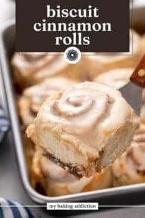 Cake server lifting up a biscuit cinnamon roll. Text overlay includes recipe name.
