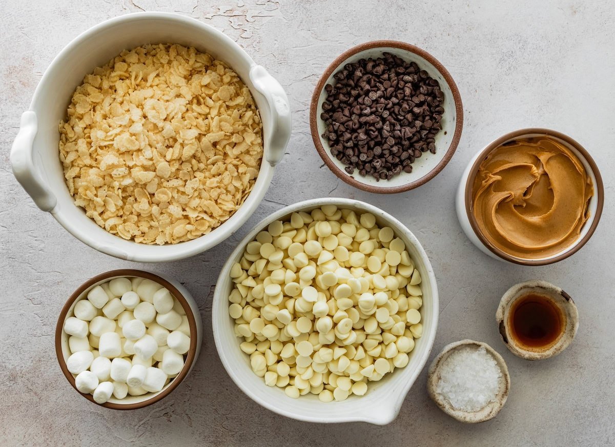 crispy rice cereal, chocolate chips, peanut butter, vanilla, salt, white chocolate chips, and marshmallows in bowls to make avalanche cookies.