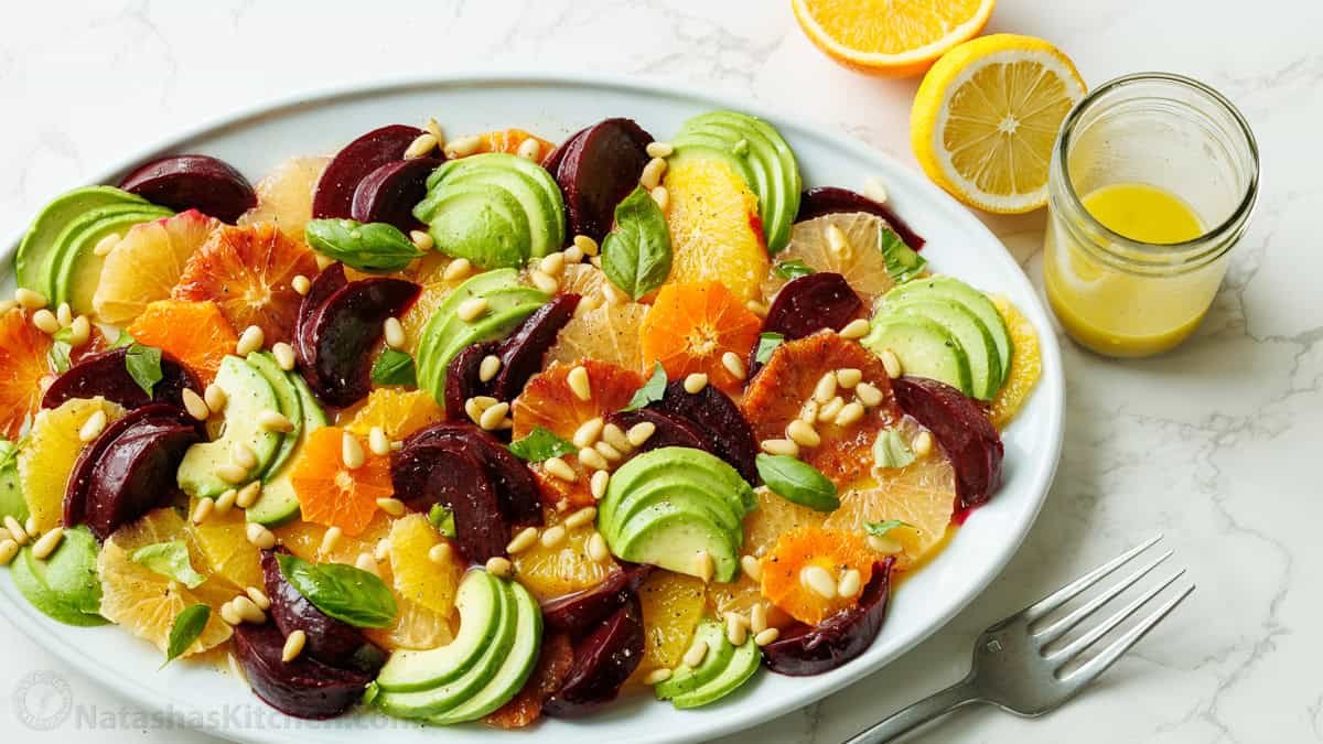 Citrus Salad is beautiful and delicious with fresh citrus, avocado, beets, basil, and pine nuts, drizzled with a bright lemon vinaigrette. Citrus salad on a white plate with lemon vinaigrette and lemons to garnish
