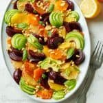 Citrus salad on a white oval plate with fork and sliced lemon