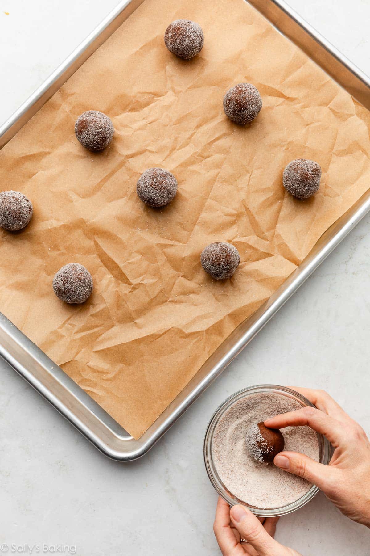 hands rolling cookie dough balls in cinnamon-sugar.