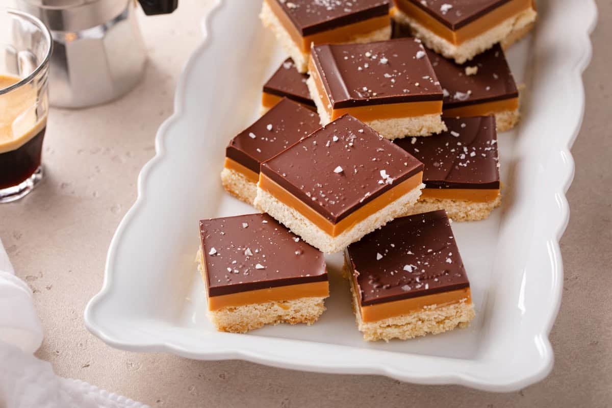 Slices of millionaire shortbread arranged on a white platter.
