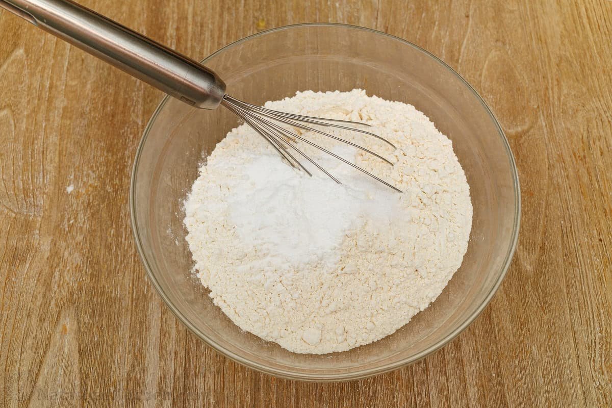mixing dry ingredients in a glass bowl with a whisk