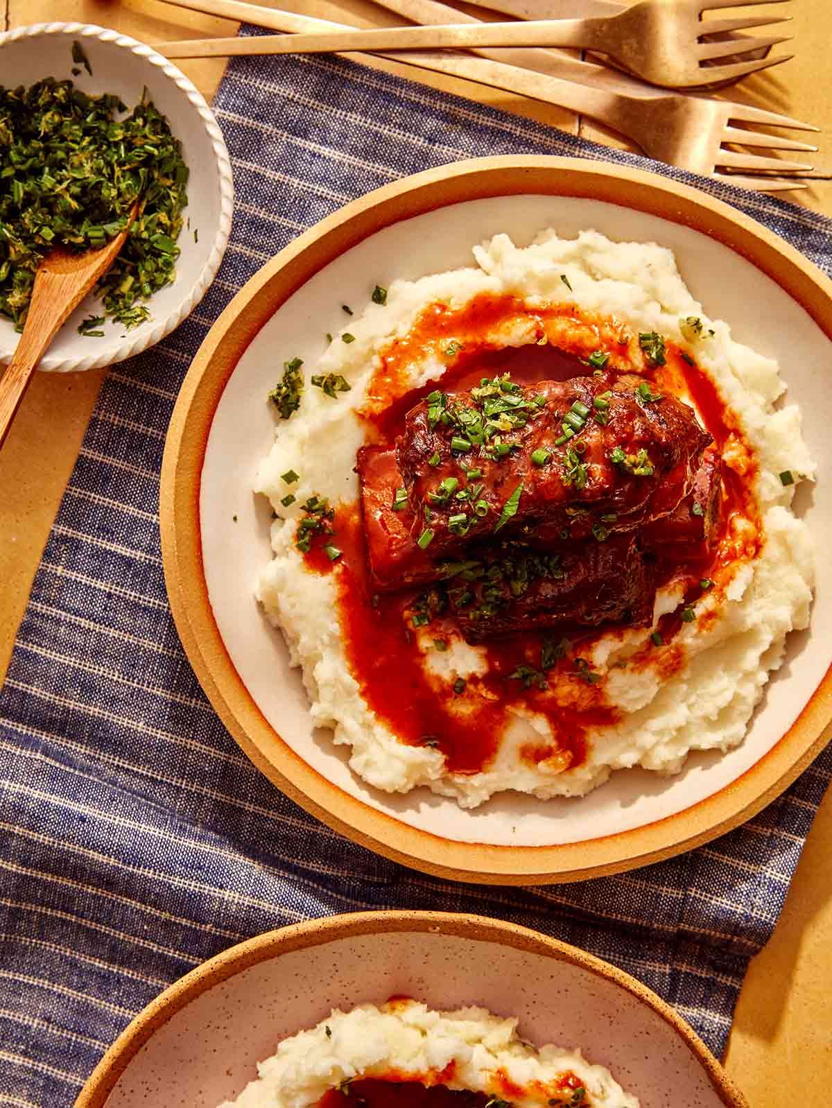 Braised short ribs in bowls with mashed potatoes.