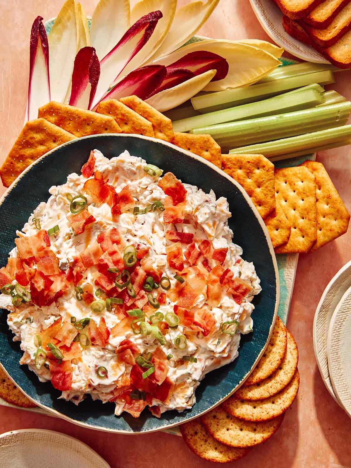Million dollar dip recipe with crackers and veggies on the side for dipping.