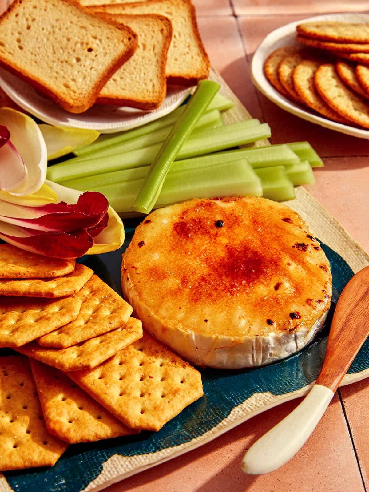 Honey Brûlée Brie being served in a platter with crackers and veggies.