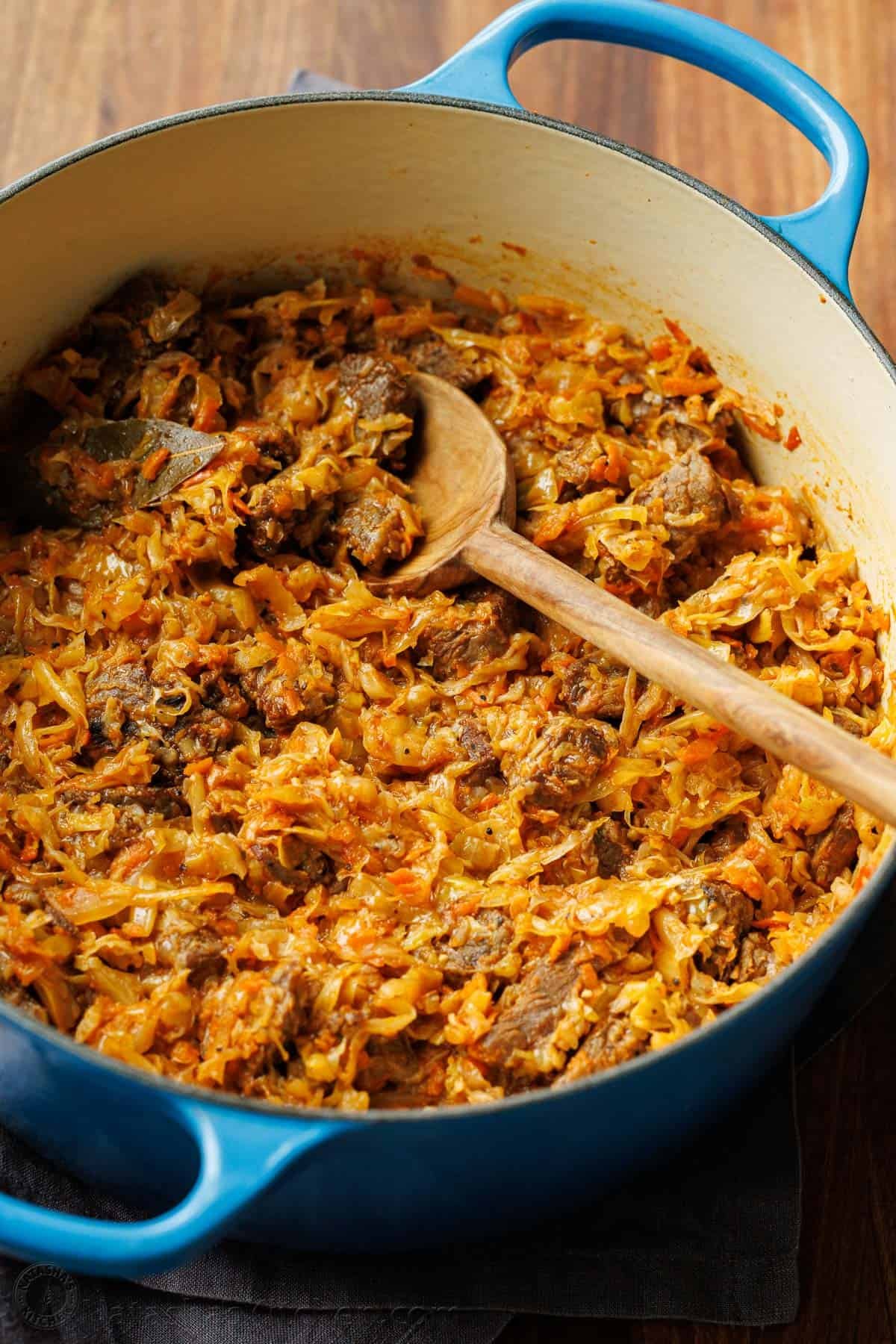 Large pot with braised cabbage stew with wooden spoon rested on the side