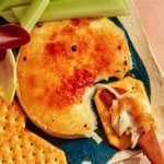 Honey Brûlée Brie on a platter with crackers and celery on the side.