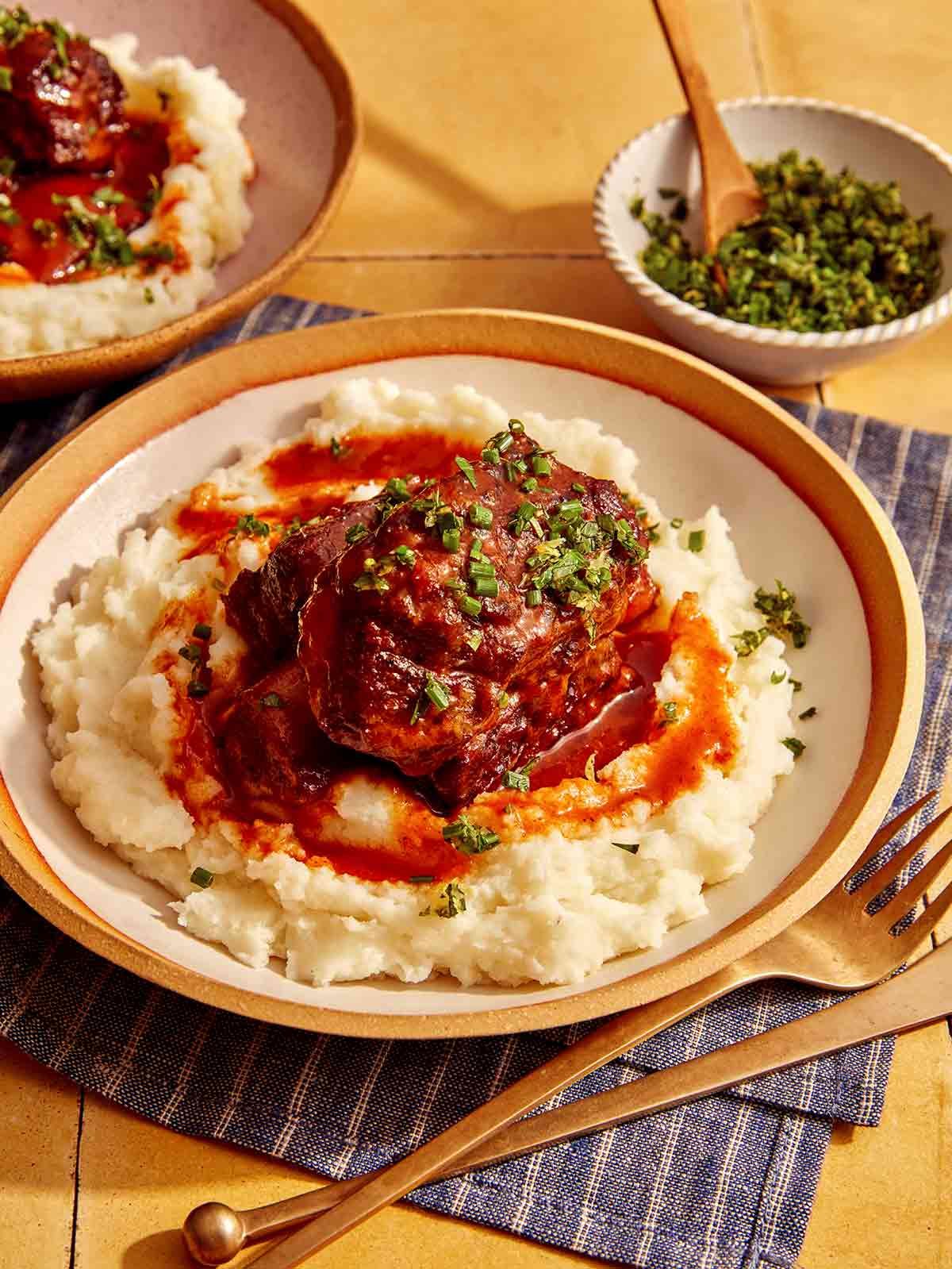 Braised short ribs on top of mashed potatoes in a bowl. 