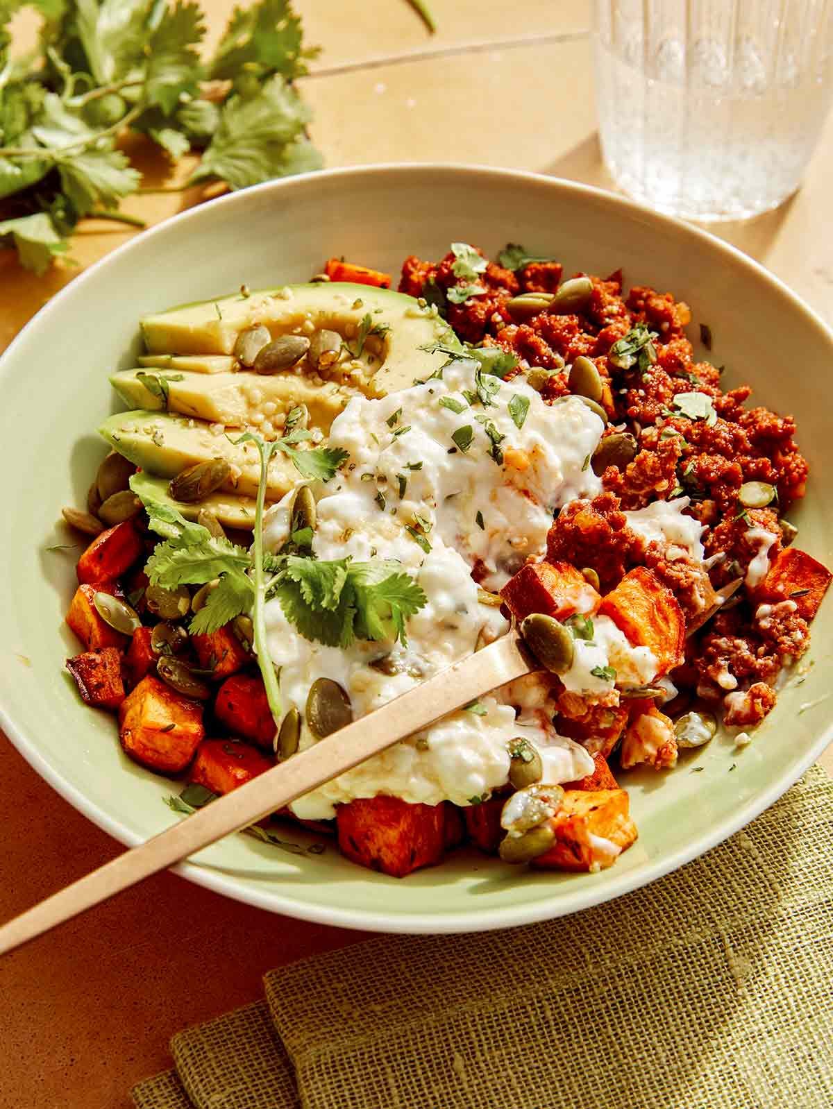 A beef protein bowl with some bites taken out and a fork in it.