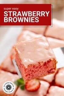 Cake server lifting up a sliced strawberry brownie. Text overlay includes recipe name.