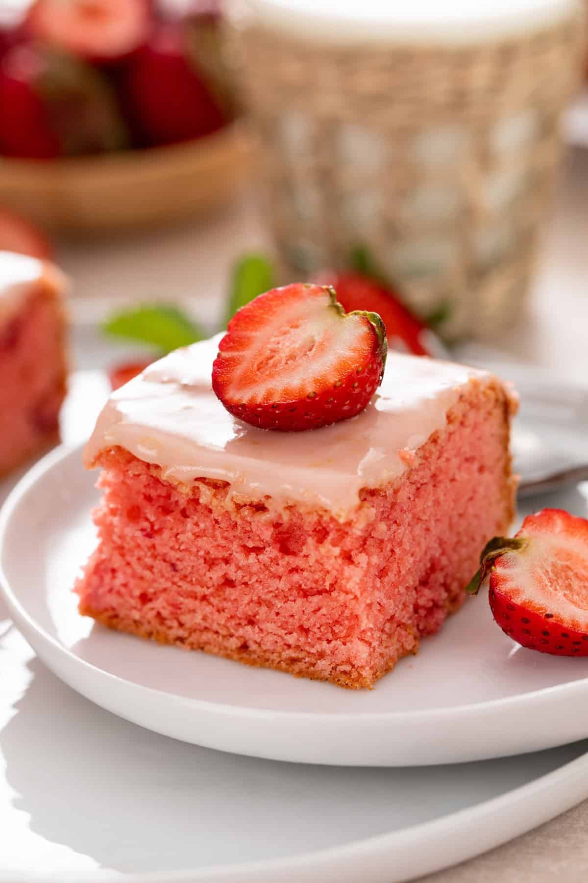 Close up image of strawberry brownie on a white plate, garnished with halved fresh strawberries.