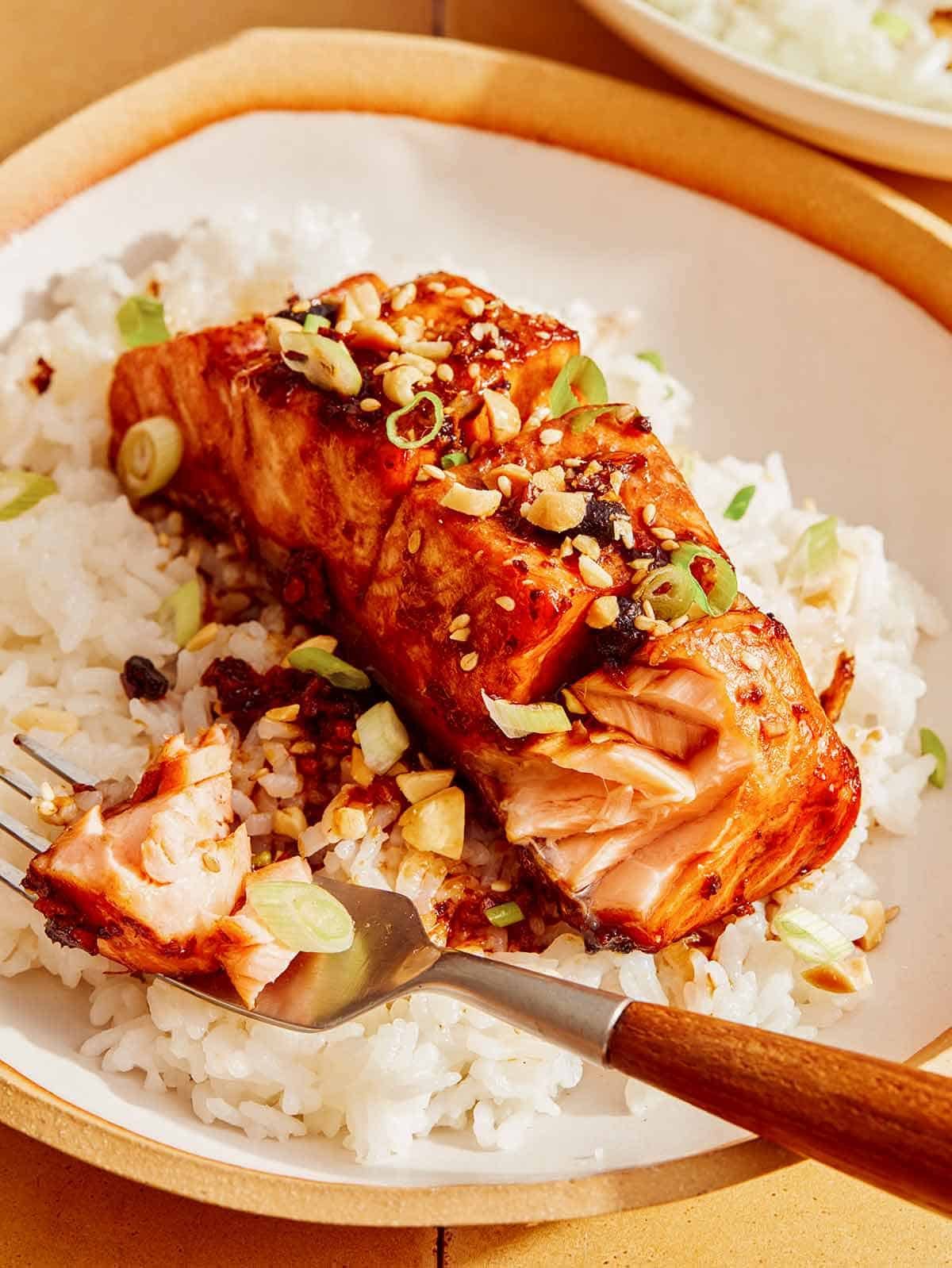 Soy glazed salmon with rice and a bite taken out of the salmon fillet.
