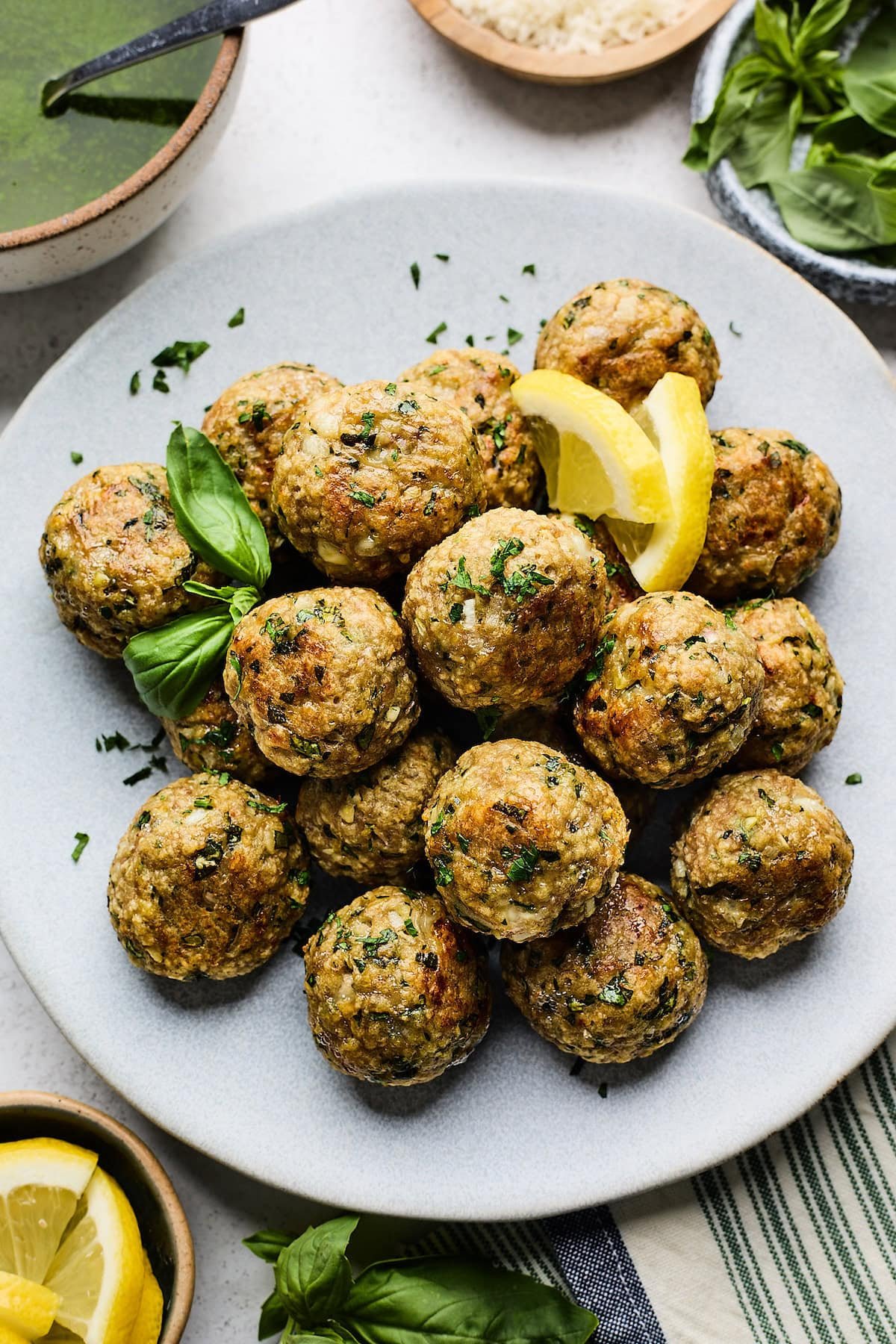 lemon herb meatballs on plate with lemon slices and herbs. 