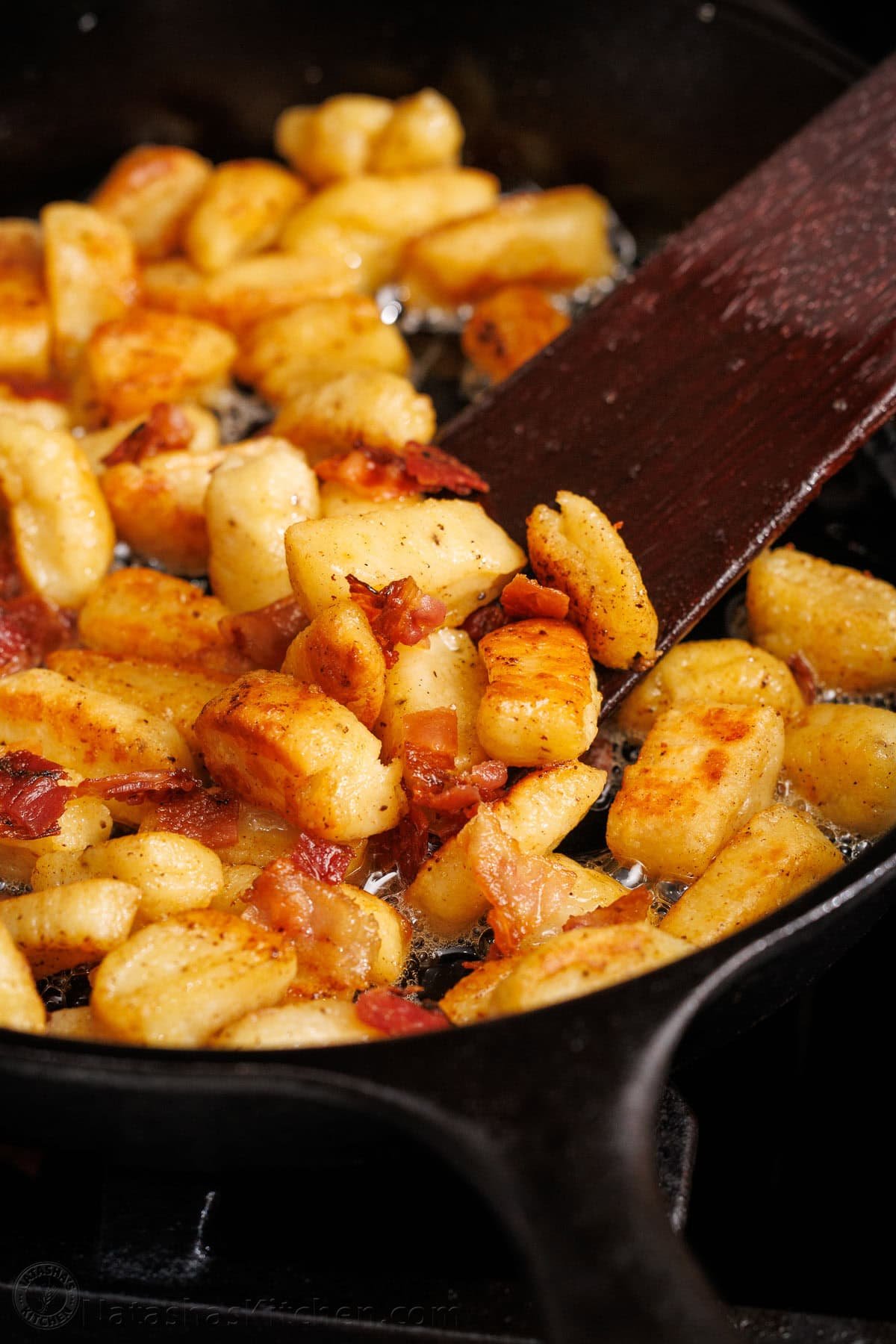 Ricotta Gnocchi satisfy the craving for gnocchi with very little effort. No need to fuss with potatoes since the star ingredient is ricotta cheese. spatula stirring ricotta gnocchi cooked in bacon butter