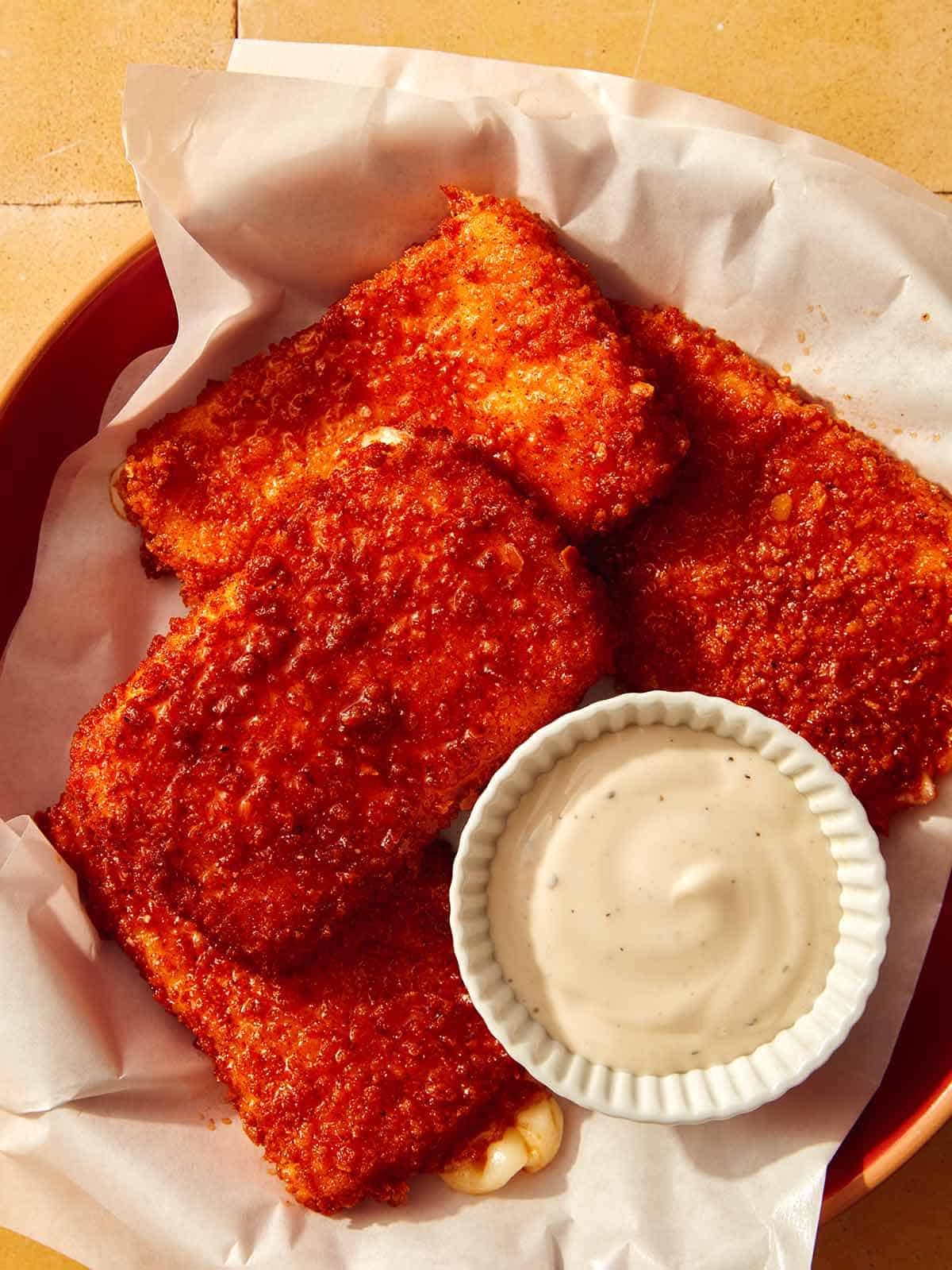Mozzarella sticks in a basket with ranch on the side.