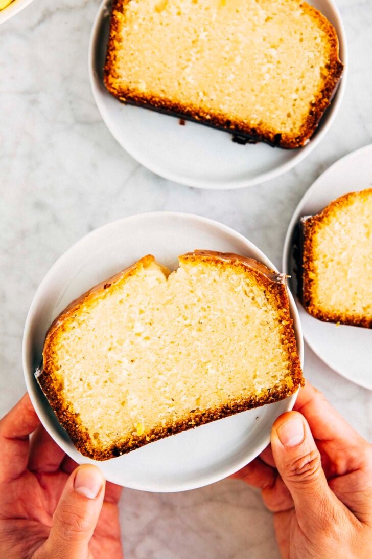 photo of Michelle from Hummingbird High holding up a slice of lemon yogurt loaf on a small white place