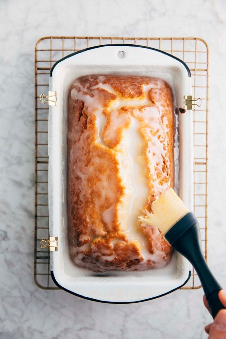 Photo of Michelle from Hummingbird High using a pastry brush to spread the lemon glaze over the cake
