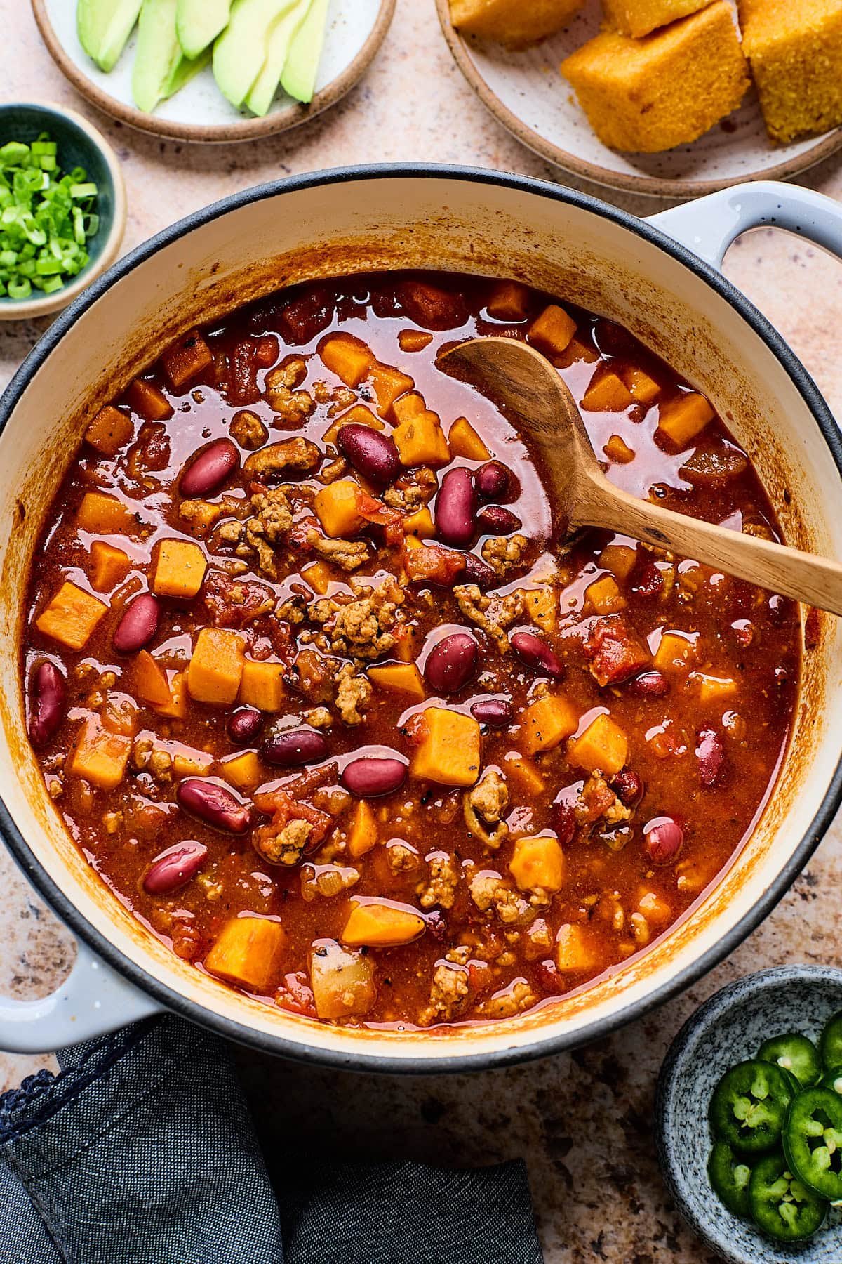turkey sweet potato chili in pot with wooden spoon.