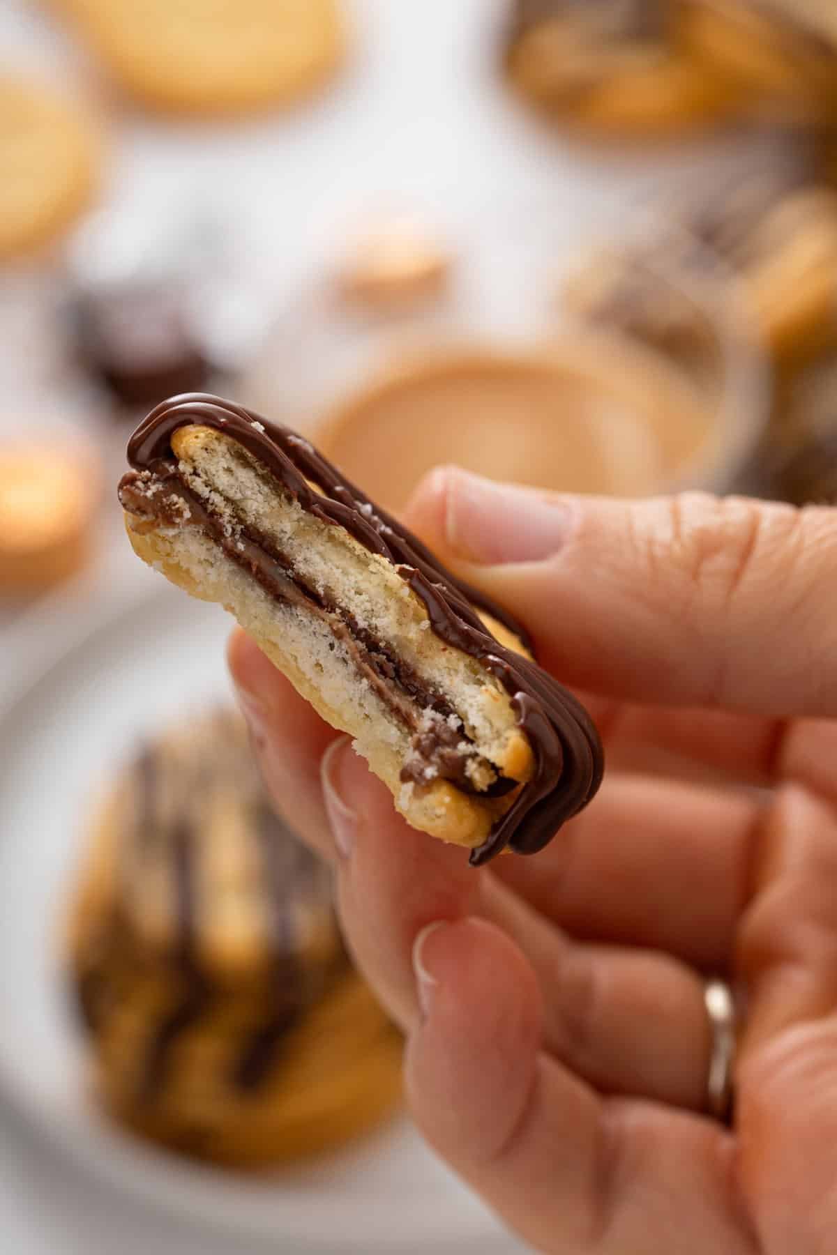 Person holding up a rolo ritz cracker cookie with a bite taken from it.