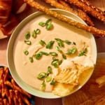 Crock pot beer cheese dip in a bowl with bread and chips all around it.