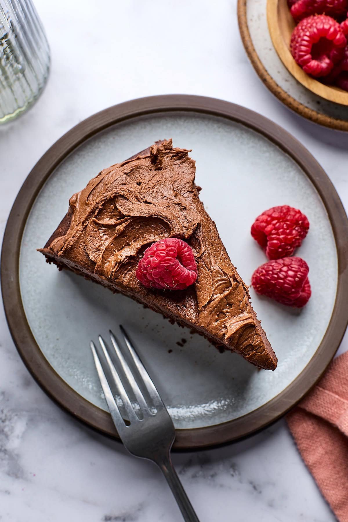 piece of chocolate yogurt cake on plate with raspberries. 