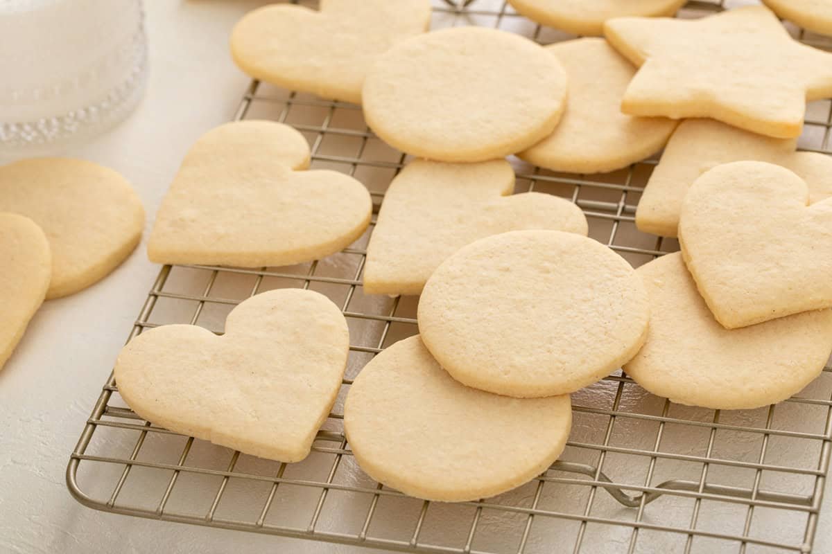 Assorted shapes of no-spread sugar cookies arranged on a wire rack on a countertop.