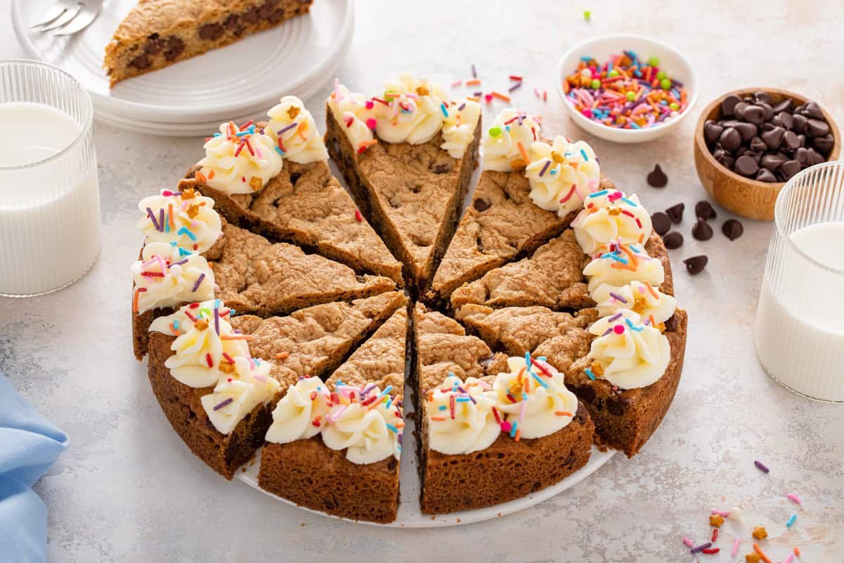 Sliced chocolate chip cookie cake decorated with frosting.