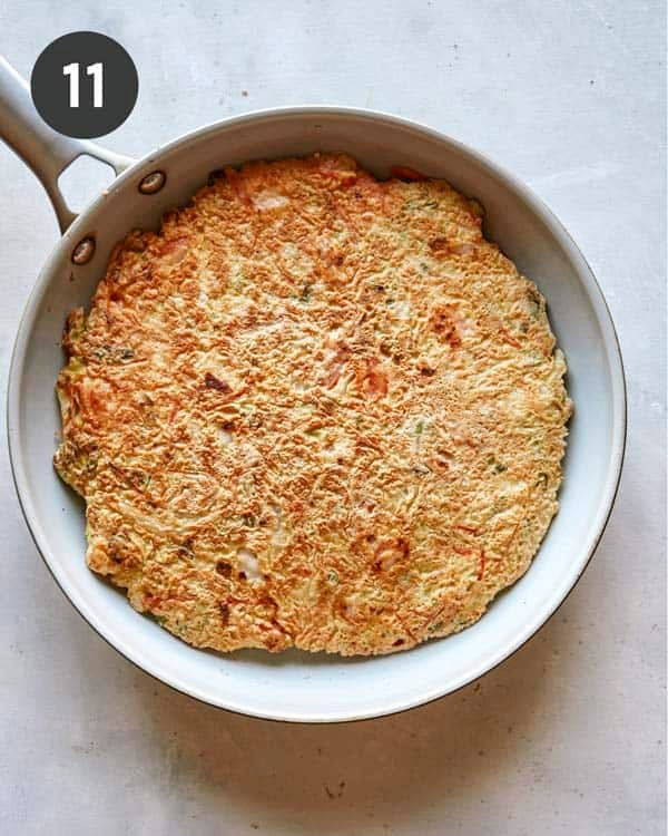 Okonomiyaki cooking in a skillet.