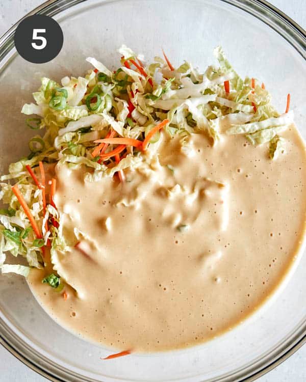 Mixing vegetables and batter in a glass bowl.
