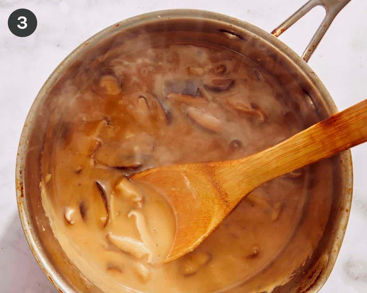 Gravy being simmered in a pot with a wooden spoon.