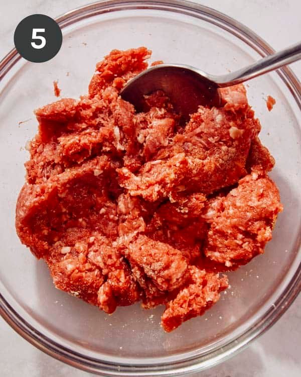 Meat being mixed together in a bowl.